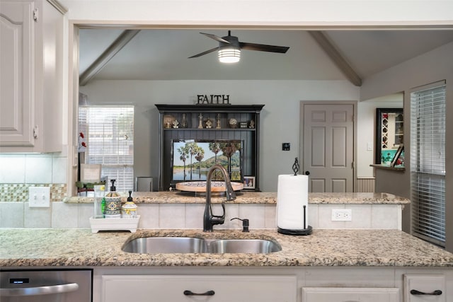 kitchen with decorative backsplash, vaulted ceiling, stainless steel dishwasher, white cabinets, and sink