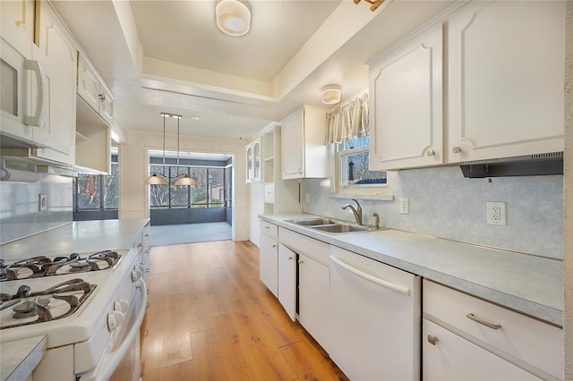 kitchen with pendant lighting, a raised ceiling, sink, white appliances, and white cabinets