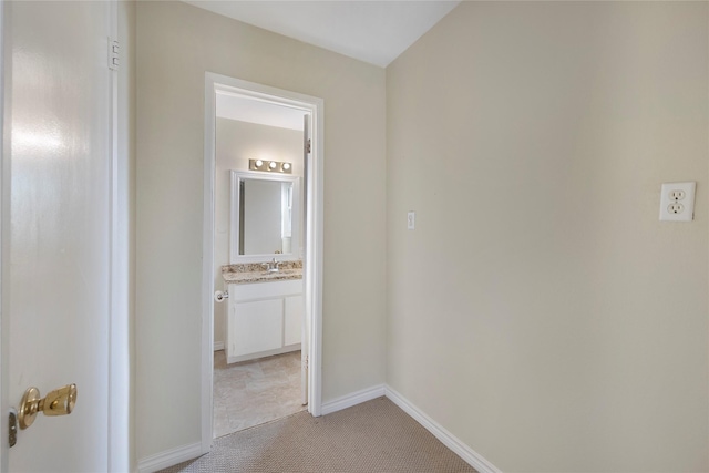 corridor featuring light colored carpet and sink