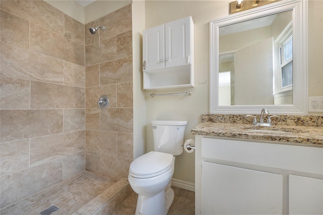 bathroom with toilet, tiled shower, and vanity