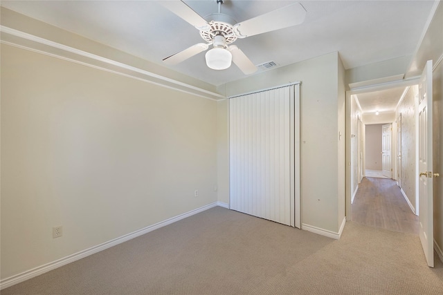 unfurnished bedroom featuring ceiling fan, light carpet, and a closet