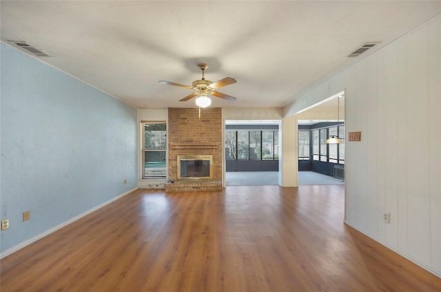 unfurnished living room with ceiling fan, a brick fireplace, and hardwood / wood-style floors