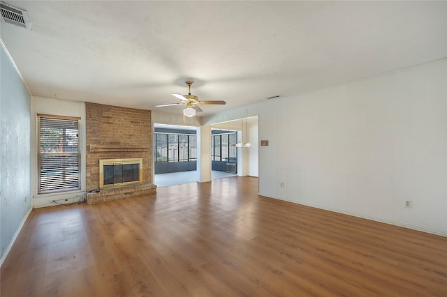 unfurnished living room featuring a brick fireplace, hardwood / wood-style floors, and ceiling fan