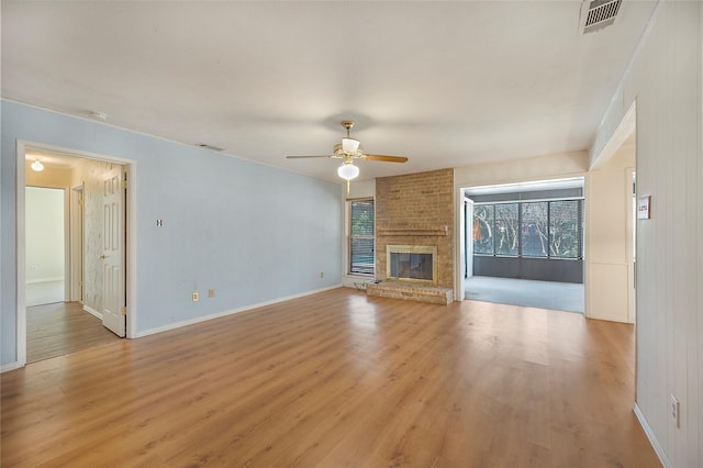 unfurnished living room featuring ceiling fan, a brick fireplace, and light hardwood / wood-style flooring