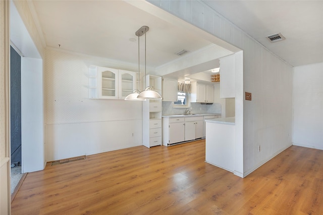 kitchen featuring hanging light fixtures, white cabinets, sink, and crown molding