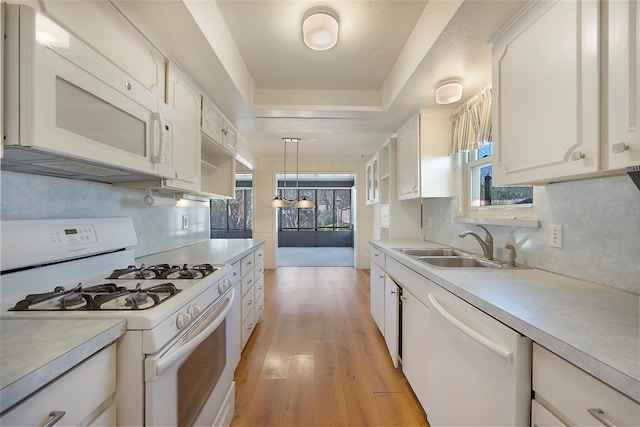 kitchen featuring light hardwood / wood-style floors, sink, white appliances, hanging light fixtures, and white cabinets