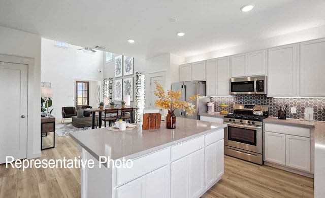 kitchen featuring white cabinets, a kitchen island, stainless steel appliances, ceiling fan, and light hardwood / wood-style flooring