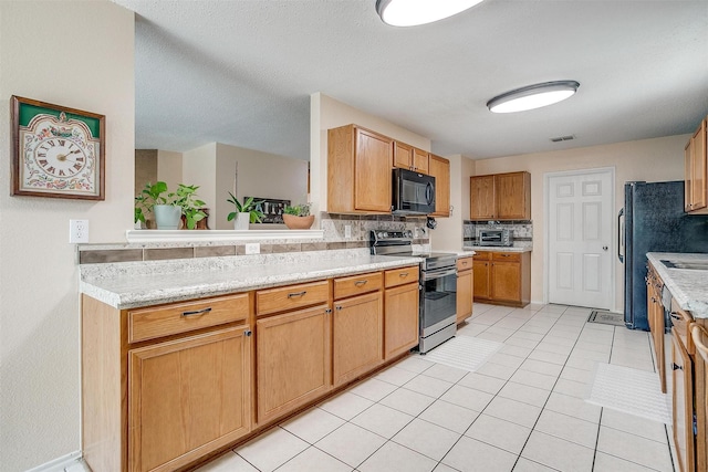 kitchen featuring light stone countertops, a textured ceiling, black appliances, backsplash, and light tile patterned floors