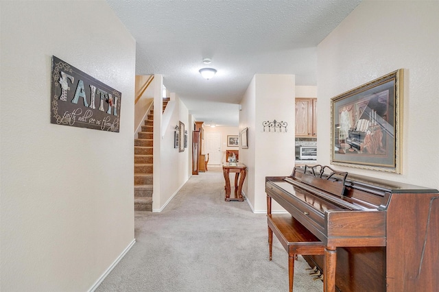 hall with light colored carpet and a textured ceiling