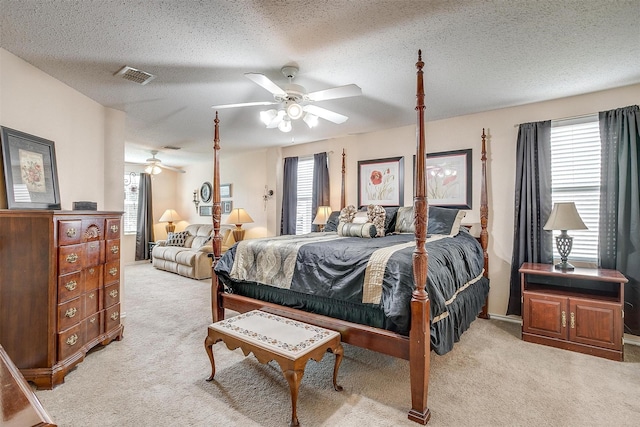 bedroom with a textured ceiling, ceiling fan, light colored carpet, and multiple windows