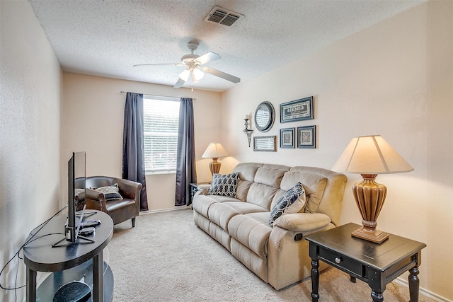 carpeted living room featuring ceiling fan and a textured ceiling