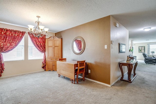 carpeted dining room featuring a wealth of natural light, a textured ceiling, and a notable chandelier