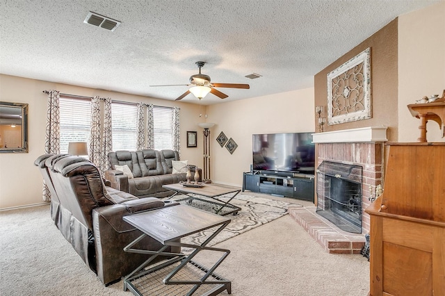 living room featuring a textured ceiling, a fireplace, light colored carpet, and ceiling fan