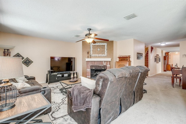 carpeted living room with ceiling fan, a fireplace, and a textured ceiling