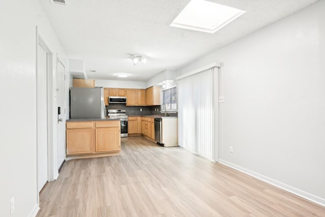 kitchen with tasteful backsplash, light hardwood / wood-style floors, a skylight, light brown cabinets, and stainless steel appliances