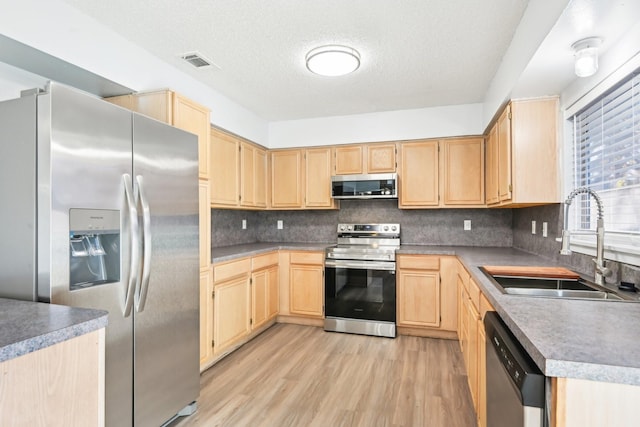 kitchen featuring stainless steel appliances, decorative backsplash, light brown cabinets, and sink