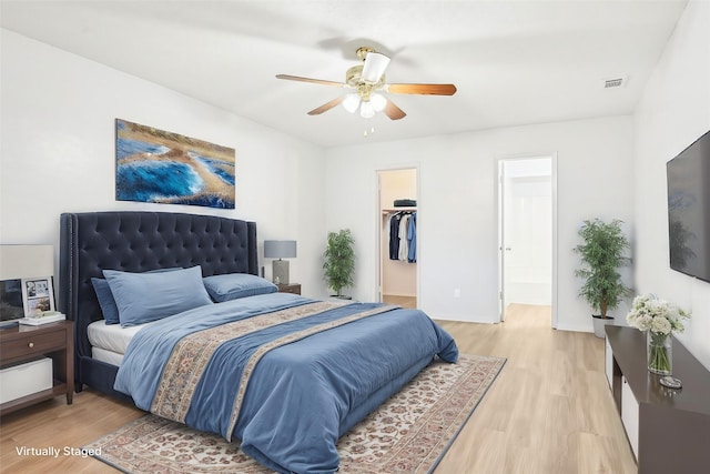 bedroom with a spacious closet, light hardwood / wood-style floors, a closet, and ceiling fan