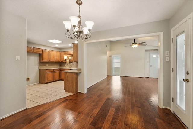 kitchen with brown cabinetry, hardwood / wood-style flooring, open floor plan, light countertops, and a sink