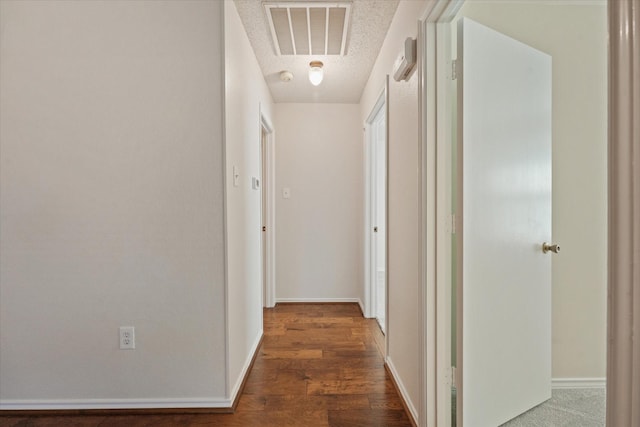 corridor with baseboards, visible vents, and wood finished floors