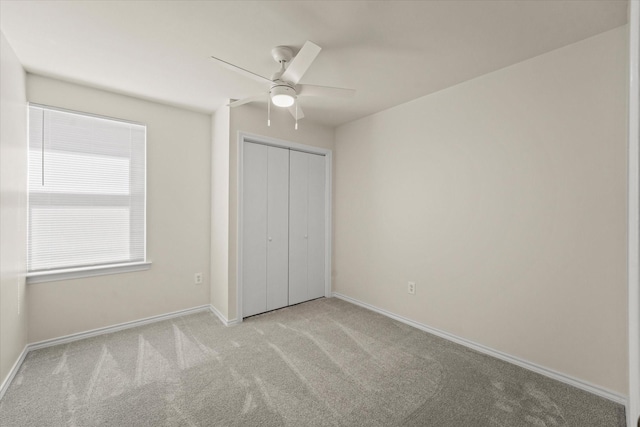 unfurnished bedroom with carpet floors, a closet, a ceiling fan, and baseboards