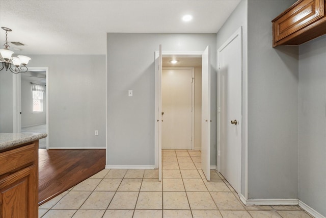 interior space featuring light tile patterned floors, baseboards, visible vents, and an inviting chandelier