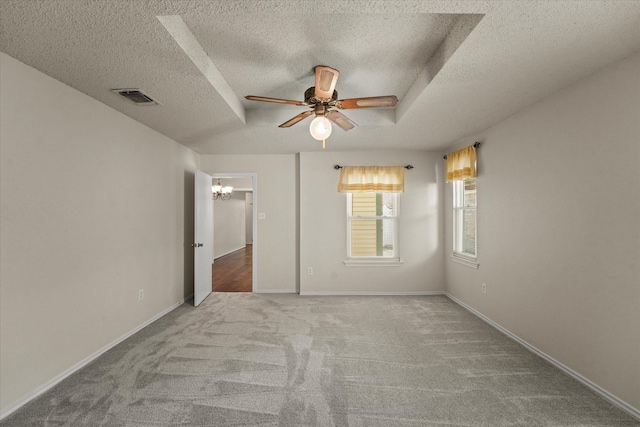 empty room with a raised ceiling, visible vents, carpet flooring, baseboards, and ceiling fan with notable chandelier