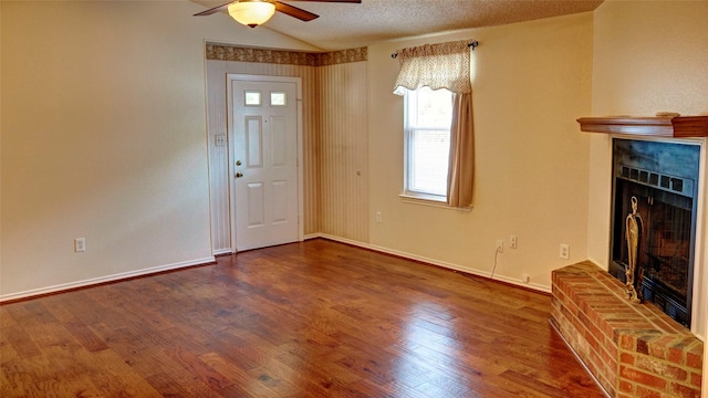 entrance foyer with a textured ceiling, lofted ceiling, ceiling fan, dark hardwood / wood-style floors, and a brick fireplace