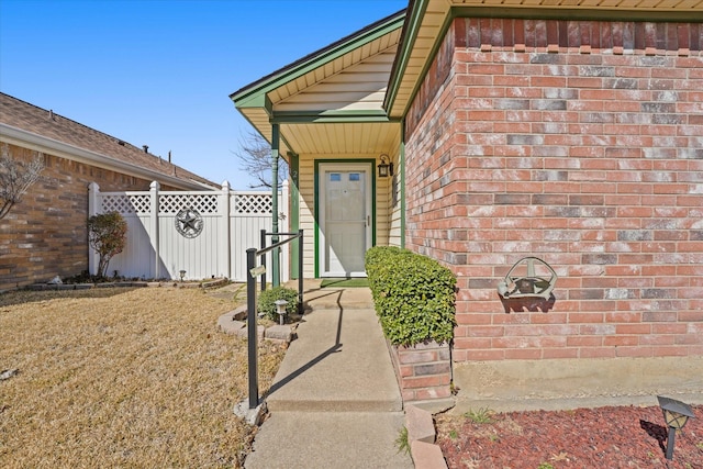 property entrance featuring brick siding and fence