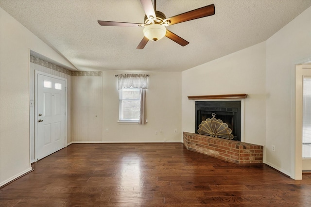 unfurnished living room with a textured ceiling, wood finished floors, baseboards, vaulted ceiling, and a brick fireplace