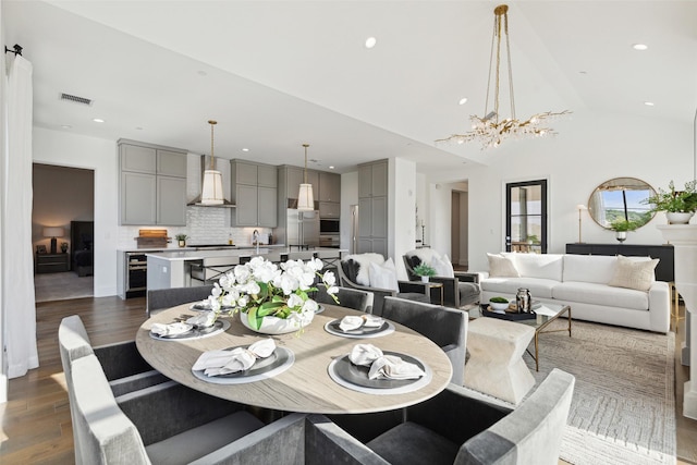 dining area featuring lofted ceiling, wine cooler, dark hardwood / wood-style floors, and an inviting chandelier