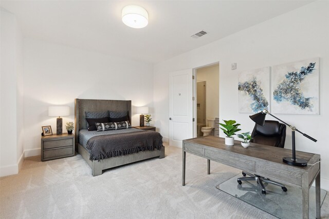 bedroom with ensuite bathroom and light colored carpet