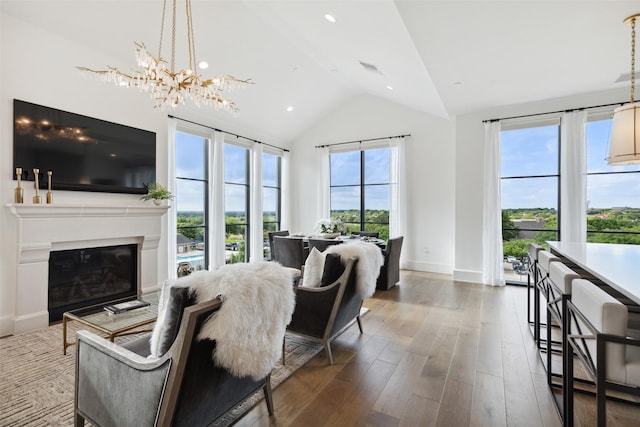 living room featuring hardwood / wood-style floors, lofted ceiling, plenty of natural light, and a notable chandelier