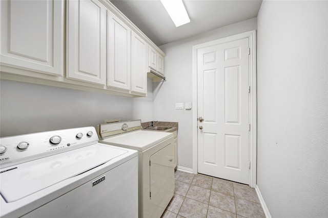 washroom featuring light tile patterned floors, sink, washing machine and clothes dryer, and cabinets