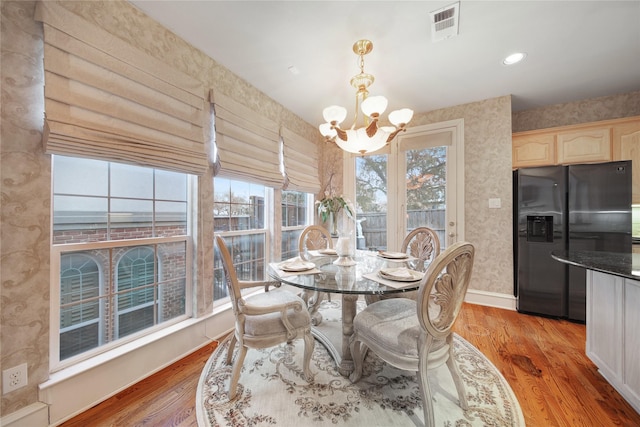 dining area featuring a healthy amount of sunlight, light wood-type flooring, and a notable chandelier