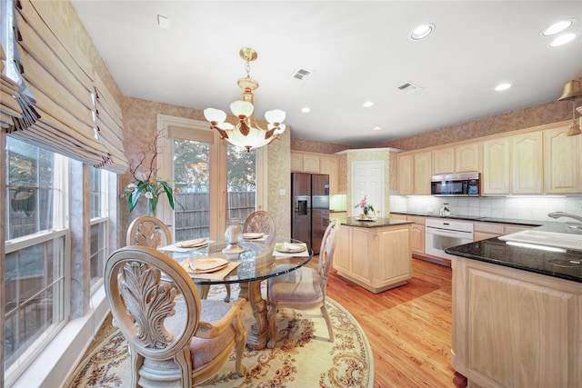 kitchen with an inviting chandelier, light hardwood / wood-style floors, stainless steel appliances, hanging light fixtures, and sink