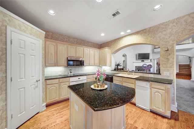 kitchen featuring tasteful backsplash, black appliances, kitchen peninsula, sink, and light wood-type flooring