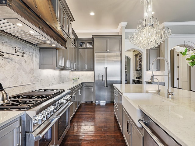 kitchen featuring decorative light fixtures, a notable chandelier, premium range hood, ornamental molding, and high quality appliances