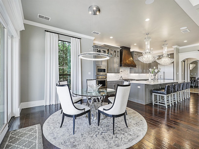 dining space with dark hardwood / wood-style flooring, ornamental molding, and a chandelier