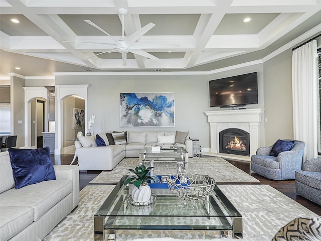 living room with hardwood / wood-style floors, coffered ceiling, ceiling fan, ornamental molding, and beam ceiling