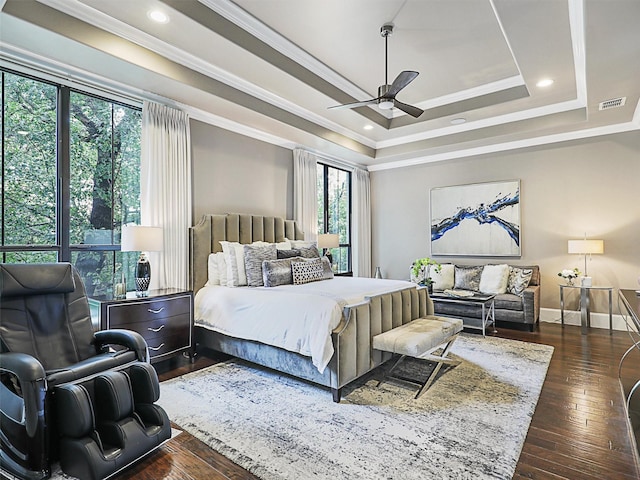 bedroom featuring a raised ceiling, ceiling fan, dark wood-type flooring, and ornamental molding