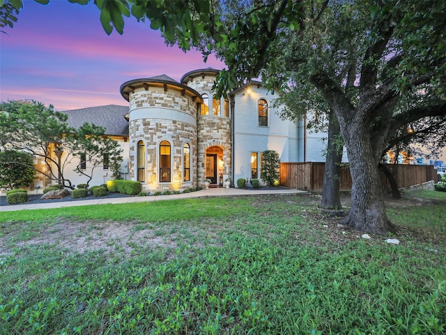 view of front of house featuring a front lawn, fence, and stone siding