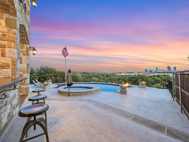 pool at dusk featuring a patio area and a pool with connected hot tub