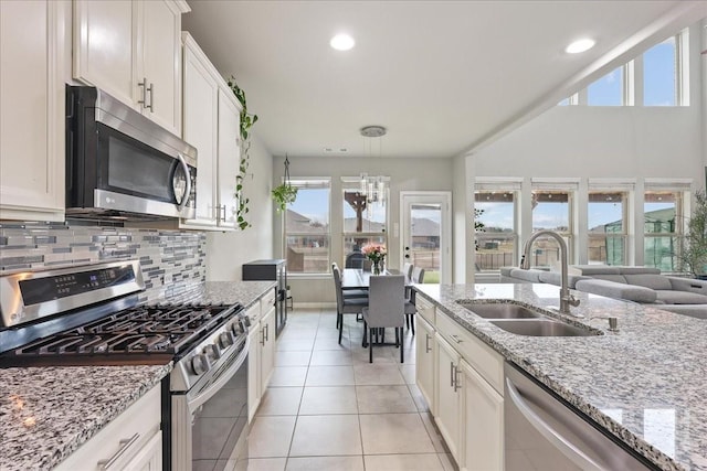 kitchen featuring sink, white cabinetry, light stone counters, light tile patterned floors, and stainless steel appliances