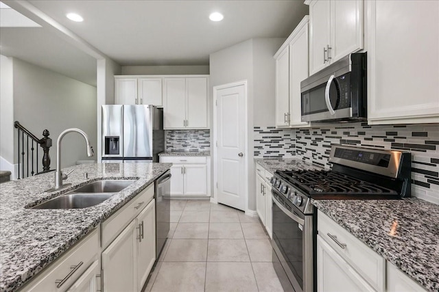 kitchen featuring sink, appliances with stainless steel finishes, backsplash, white cabinets, and light tile patterned flooring