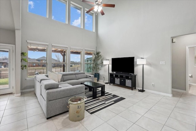 tiled living room featuring ceiling fan, a towering ceiling, and a wealth of natural light