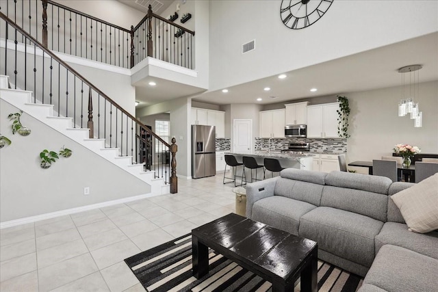 tiled living room with a notable chandelier and a high ceiling