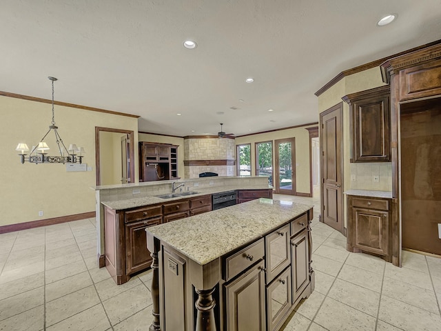 kitchen with light stone countertops, a center island, tasteful backsplash, sink, and hanging light fixtures