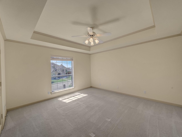 carpeted spare room featuring ceiling fan, ornamental molding, and a raised ceiling