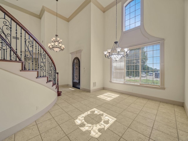 entrance foyer with a towering ceiling, crown molding, and a chandelier