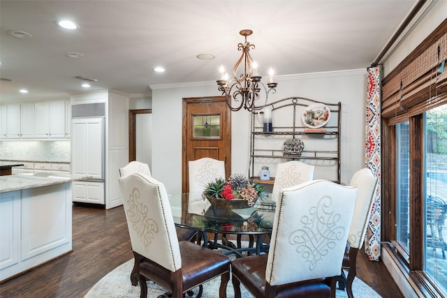 dining room with dark wood-type flooring, ornamental molding, and a chandelier